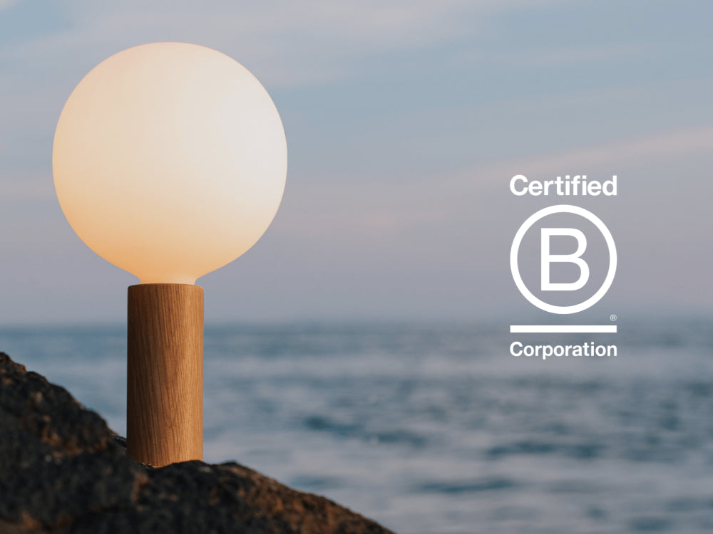 Tala Knuckle Table Lamp in Oak with Sphere bulb photographed by the shore