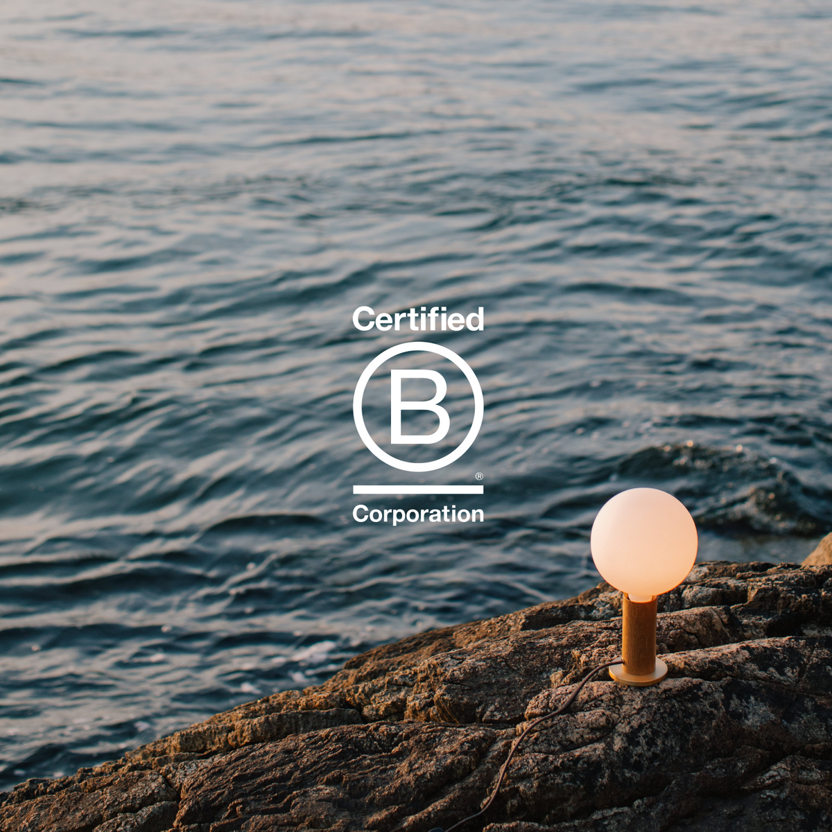 A Knuckle Table Lamp + Sphere IV facing the sea, showing Tala's commitment to people, planet, and purpose as a Certified B Corporation.