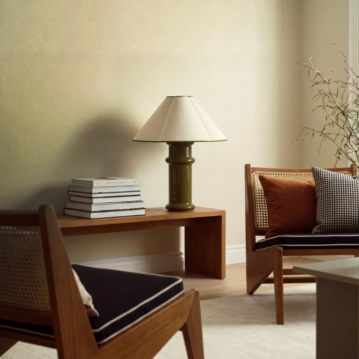 Lit Heath Table Lamp on a wooden bench with a stack of books, between two cane-backed lounge chairs