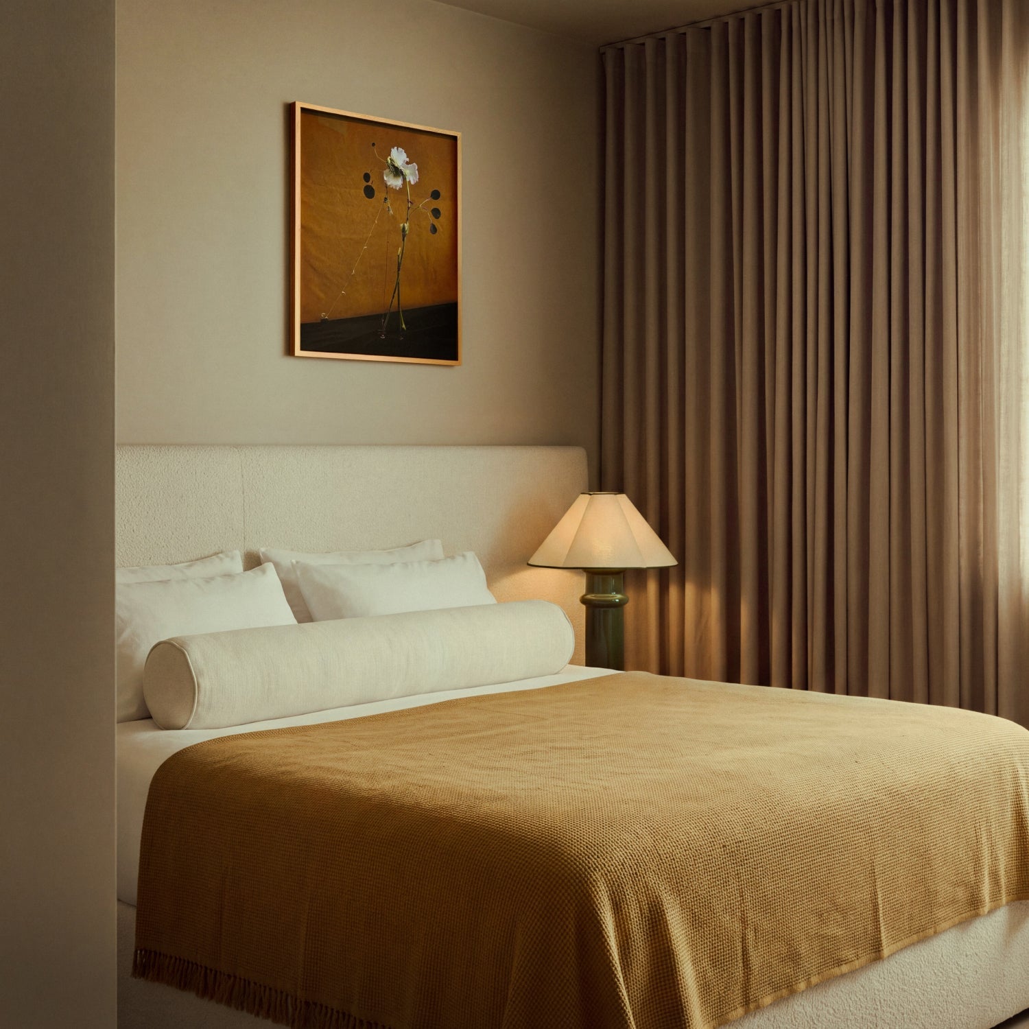 Lit Heath Table Lamp beside a bed with a white boucle headboard and a mustard throw