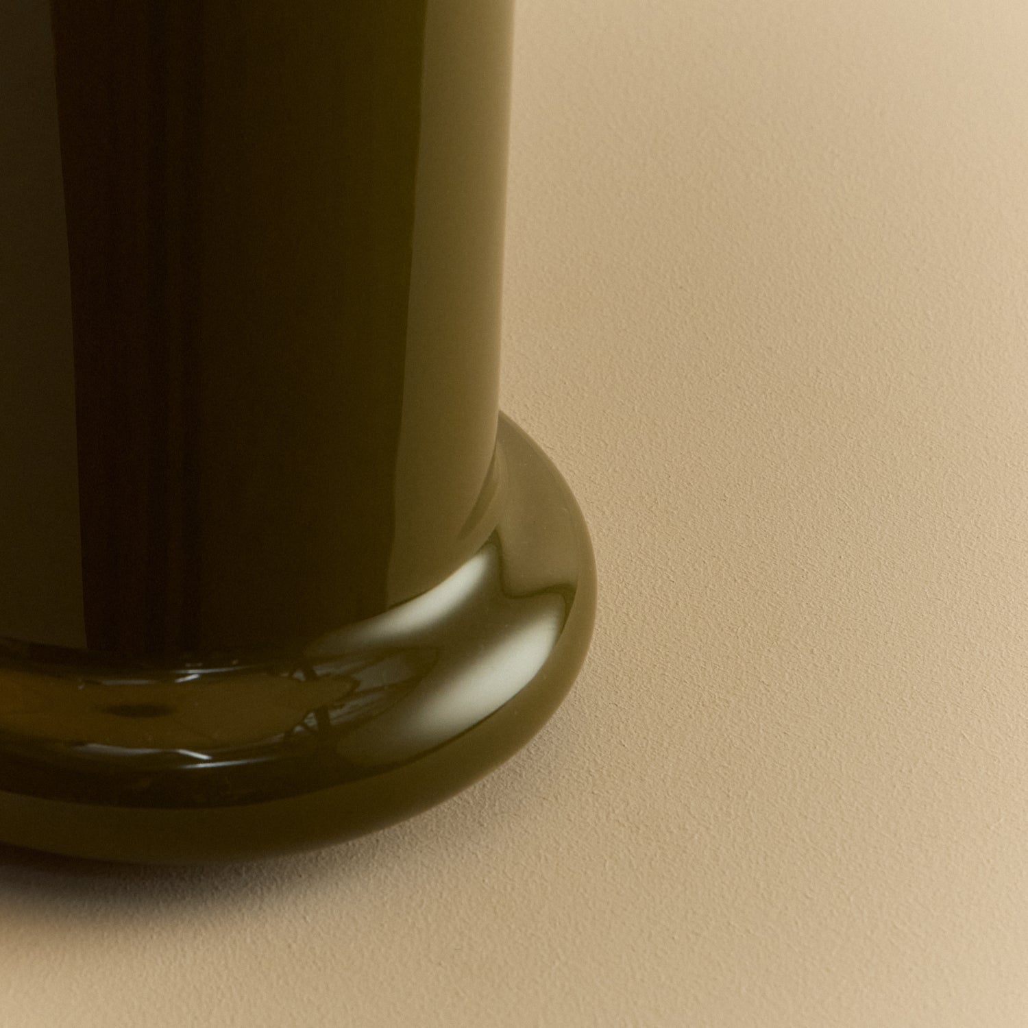 Close-up of the rounded foot of the Heath Table Lamp's glossy olive green ceramic base