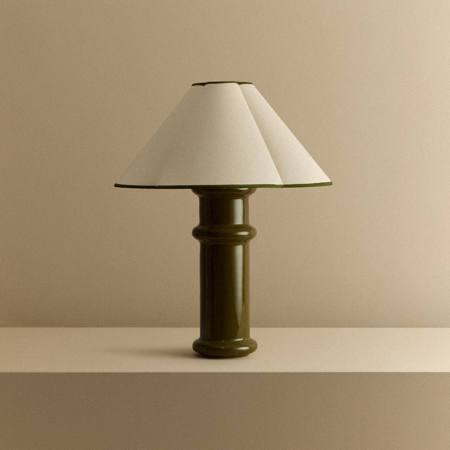 Heath Table Lamp in Olive Green switched off: a glossy olive green ceramic base with a natural cotton shade edged in green