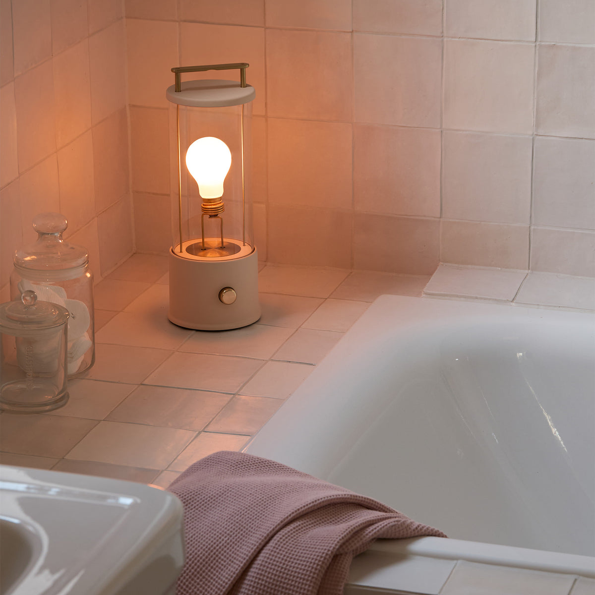 Lifestyle shot of Tala Muse Portable Lamp in Setting Plaster Pink, adding style and light to the bathroom.